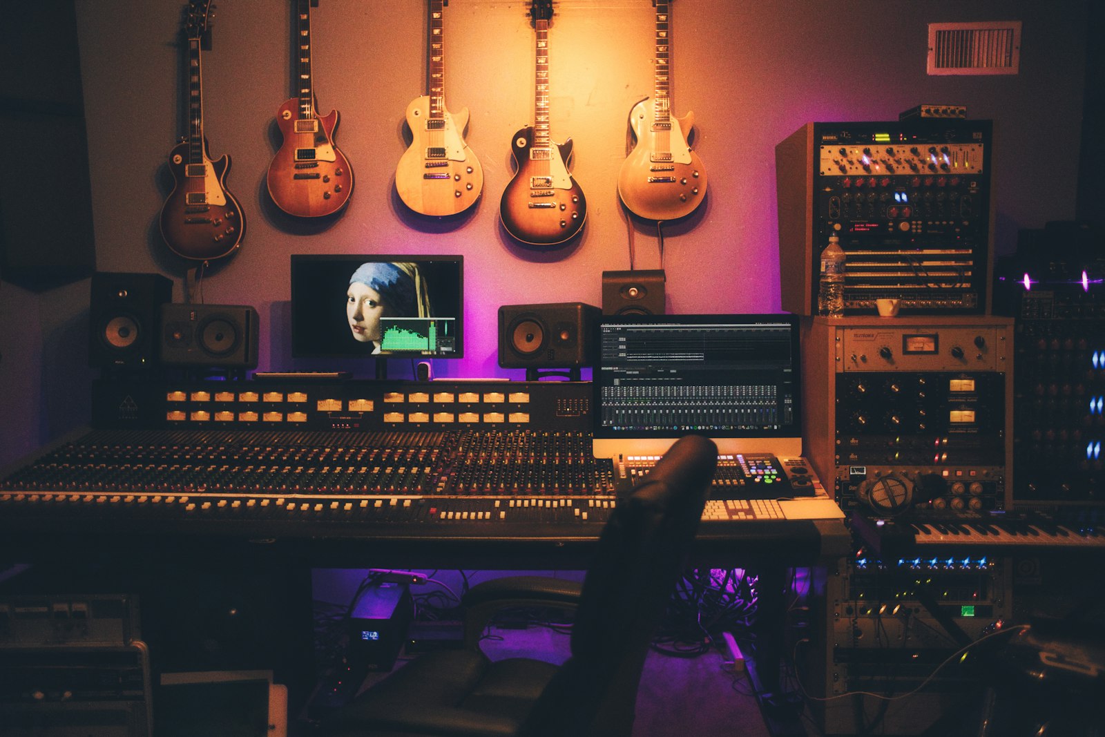 A close-up of an audio mixing console with illuminated faders.