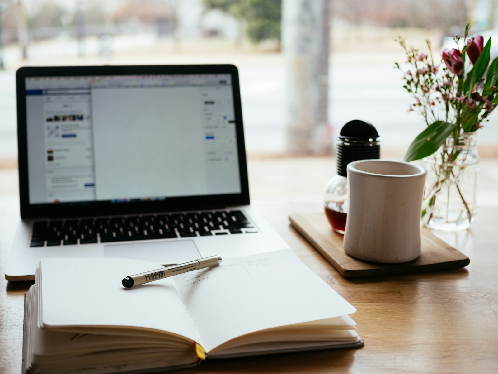 A laptop open on a desk in warm light, set up for online learning.